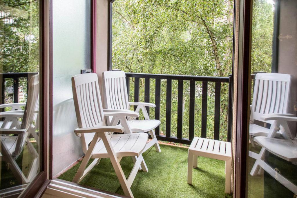 cztery białe krzesła ustawione na osłoniętym ganku w obiekcie Résidence Les Embruns - maeva Home - Studio 4 Personnes Confort MAE-1715 w mieście Deauville