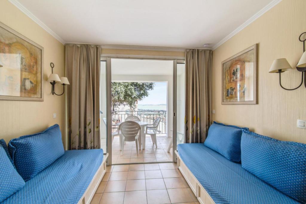 un salon avec des canapés bleus et un balcon dans l'établissement Les Appartements aux Restanques du Golfe de St Tropez - maeva Home - Appartem 88, à Grimaud