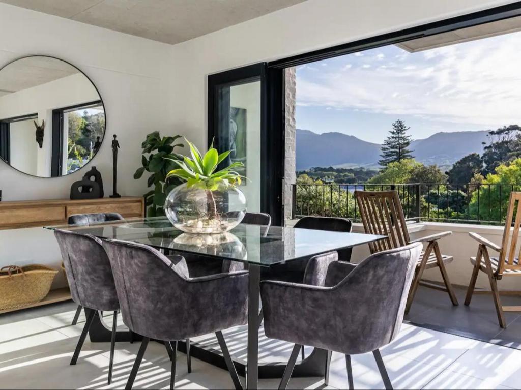 a dining room with a glass table and chairs and a large window at Luxury Accomodation at the Alphen Glen in Cape Town