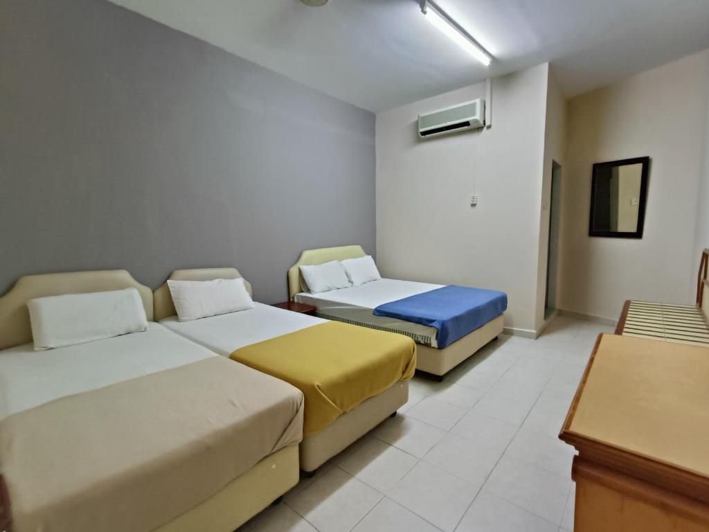 a hotel room with two beds and a desk at Kota Lodge in Melaka