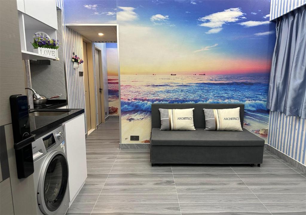 uma sala de estar com um sofá e uma pintura do oceano em 3BR Romantic apt, 2mins MTR, 8pax em Hong Kong