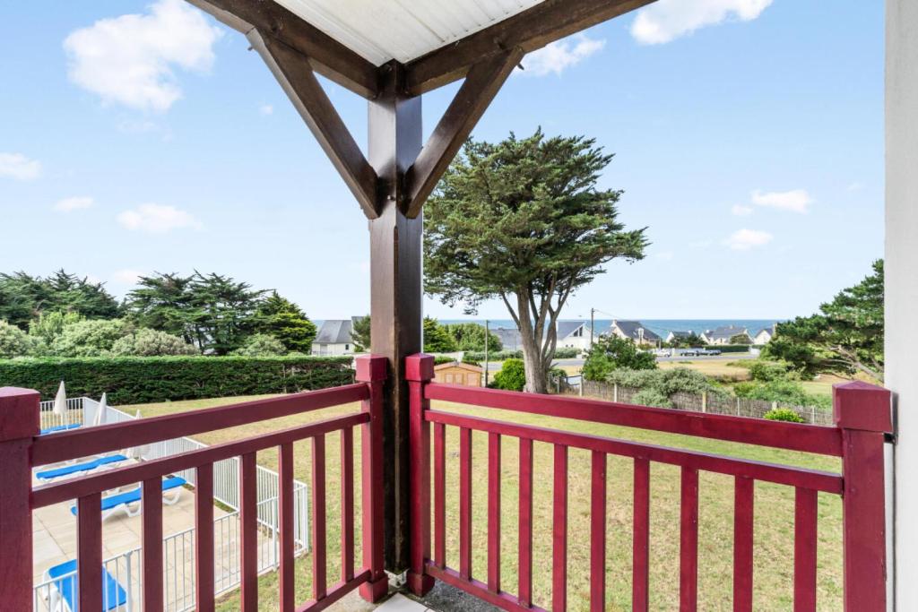 une clôture rouge sur un balcon avec vue sur un parc dans l'établissement Le Domaine De Cramphore - maeva Home - Appartement 2 pièces 4 personnes Confort MAE-5518, au Pouliguen