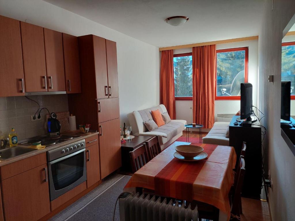 eine Küche mit einem Tisch und ein Wohnzimmer in der Unterkunft Apartman Pahuljica Vlašić in Vlasic