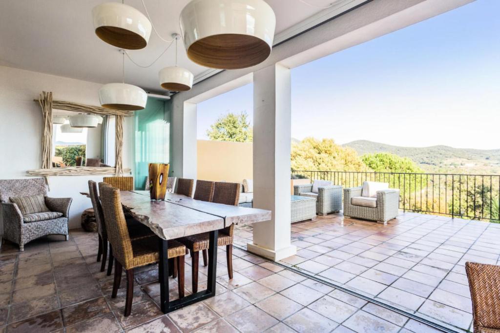 une salle à manger avec une table et des chaises et un balcon dans l'établissement Les Bastides aux Restanques du Golfe de St Tropez - maeva Home - Bastide 3 pièces 6 personnes vue mer - Prestige - Super Home MAE-0266, à Grimaud