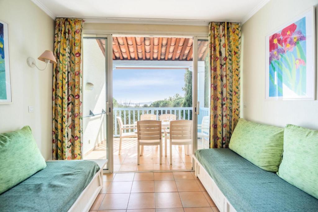 Cette chambre comprend deux lits et un balcon avec une table. dans l'établissement Les Appartements aux Restanques du Golfe de St Tropez - maeva Home - Appartement duplex 3 Pièces 6 Personnes - Confort - vue Mer MAE-7771, à Grimaud