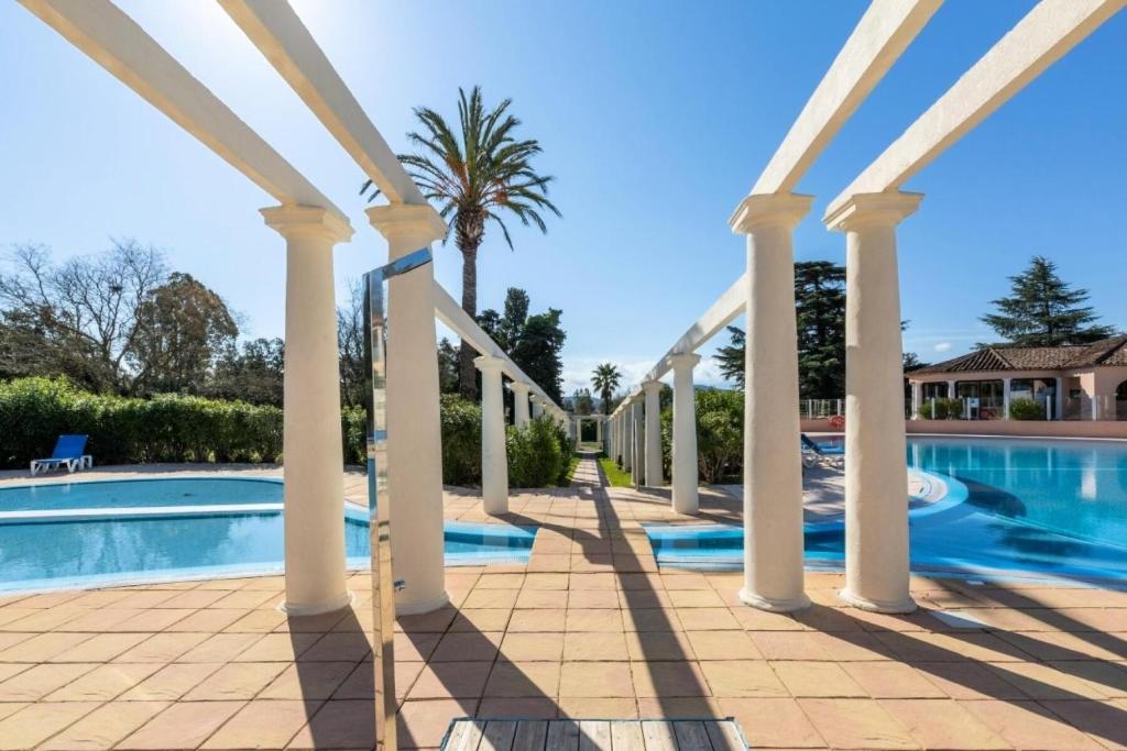 - une vue sur la piscine bordée de colonnes et d'un palmier dans l'établissement Résidence Les Parcs de Grimaud - maeva Home - Appartement 2 pièces 5 personnes - Confort MAE-6628, à Grimaud