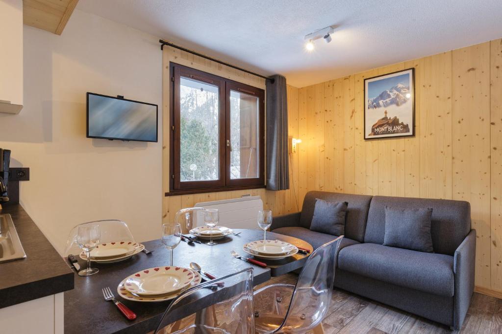 a living room with a table and a couch at Hameau Des Grands Montets - Apartment 127 - Happy Rentals in Chamonix