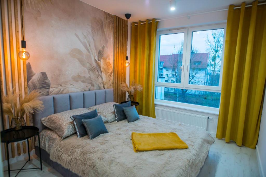 a bedroom with a bed with a yellow blanket on it at Nowoczesny apartament Ludova in Biskupiec