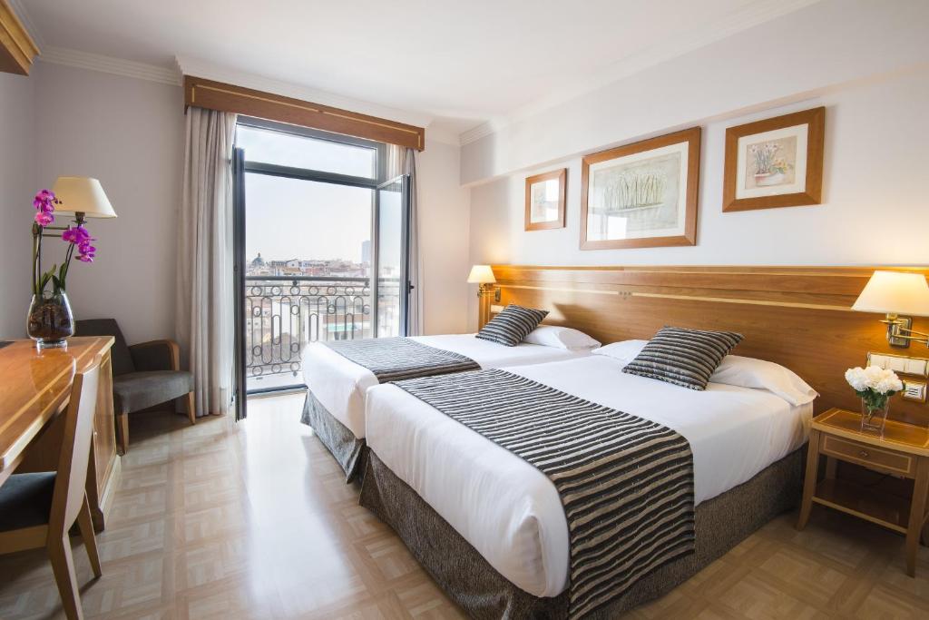 2 łóżka w pokoju hotelowym z dużym oknem w obiekcie VP Jardín Metropolitano w Madrycie