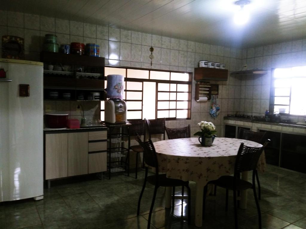 a kitchen with a table and chairs and a table and a refrigerator at Aluguel para Temporada in São Roque de Minas