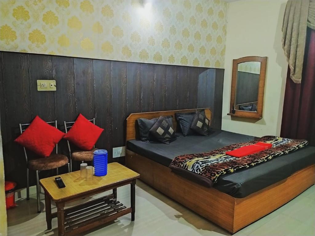 a bedroom with a bed with red pillows and a table at SUMAN GUEST HOUSE in Katra