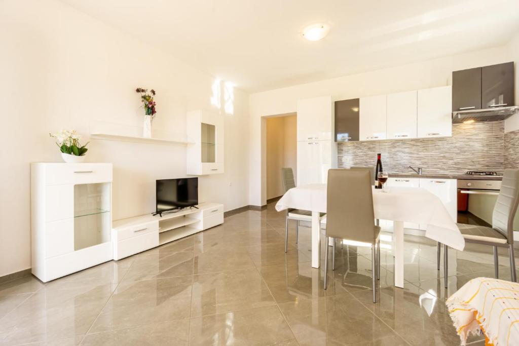uma cozinha e sala de jantar com armários brancos e uma mesa em Reful Top modern facility with large terrace or balcony em Metajna