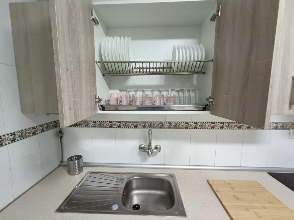 a kitchen with a sink and a shelf with dishes at Piso Avenida junto a la Playa in Cádiz