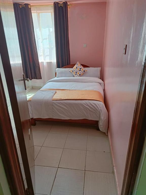 a small bedroom with a bed and a window at Sislink Hotel in Nairobi