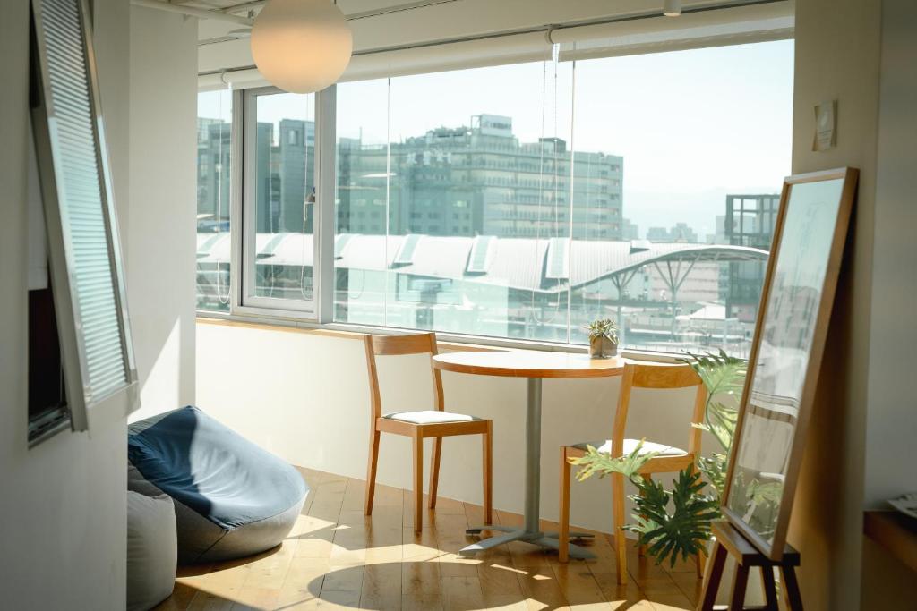 um quarto com uma mesa e cadeiras e uma grande janela em Norden Ruder Hostel Taichung em Taichung
