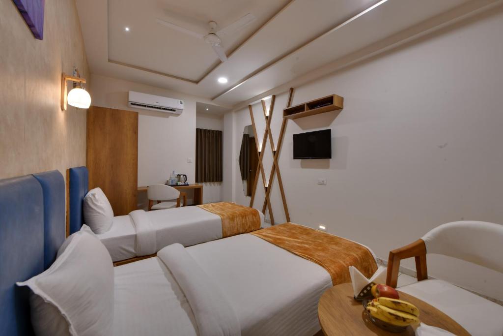pokój hotelowy z 2 łóżkami i stołem w obiekcie Click Hotel Tulsi Jamnagar w mieście Jamnagar