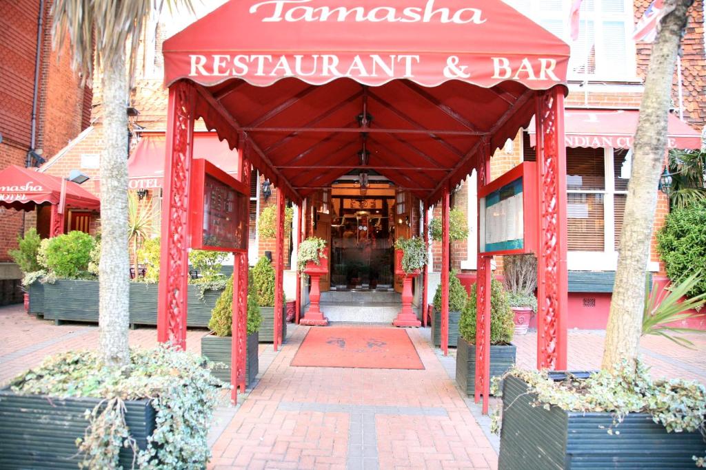 una entrada a un restaurante y bar con toldo rojo en Tamasha Hotel, en Bromley