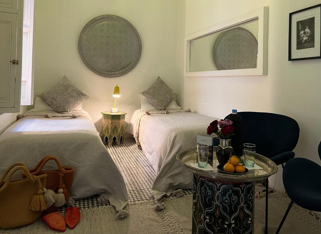 una camera da letto con due letti e un tavolo con una lampada di Riad Albatoul a Marrakech