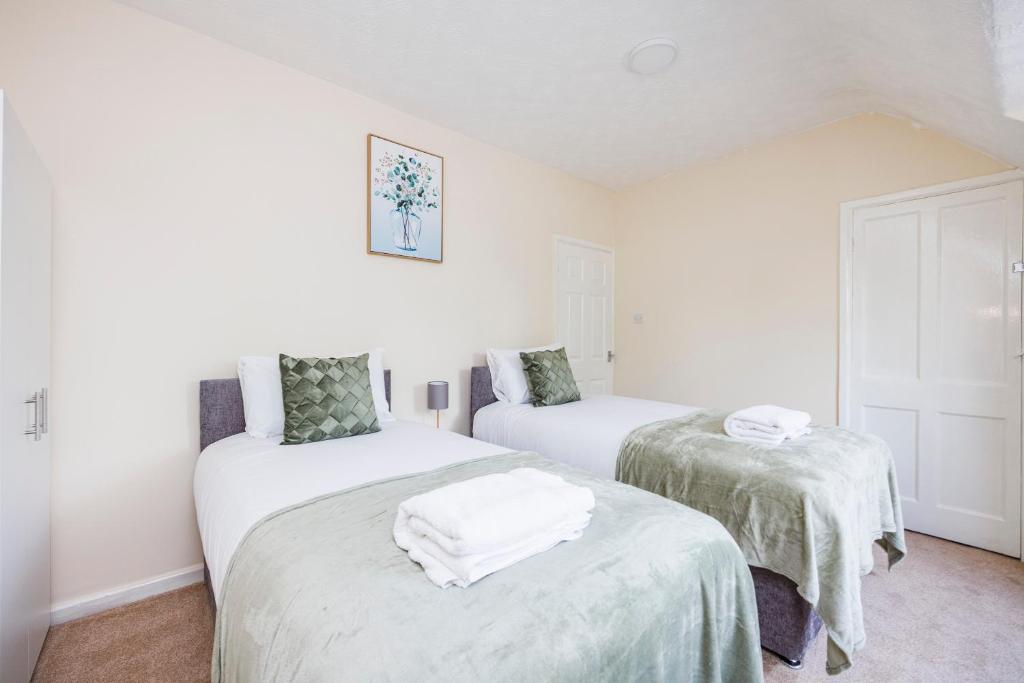 duas camas num quarto com lençóis brancos em Newly Launched 2 Bed Home in Dagenham ~London with free Wifi & Off-Street Parking em Goodmayes