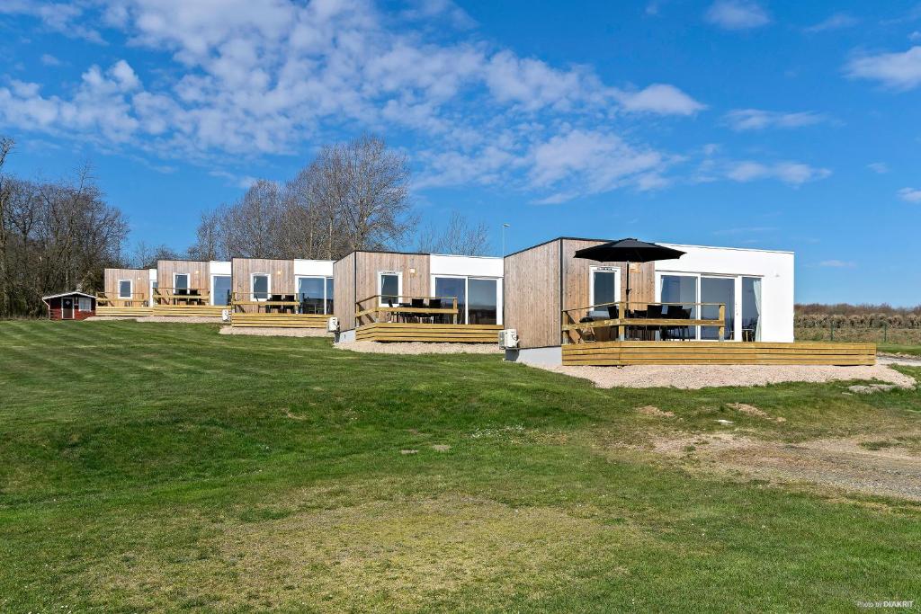 a building with tables and an umbrella on a field at First Camp Röstånga-Söderåsen in Röstånga