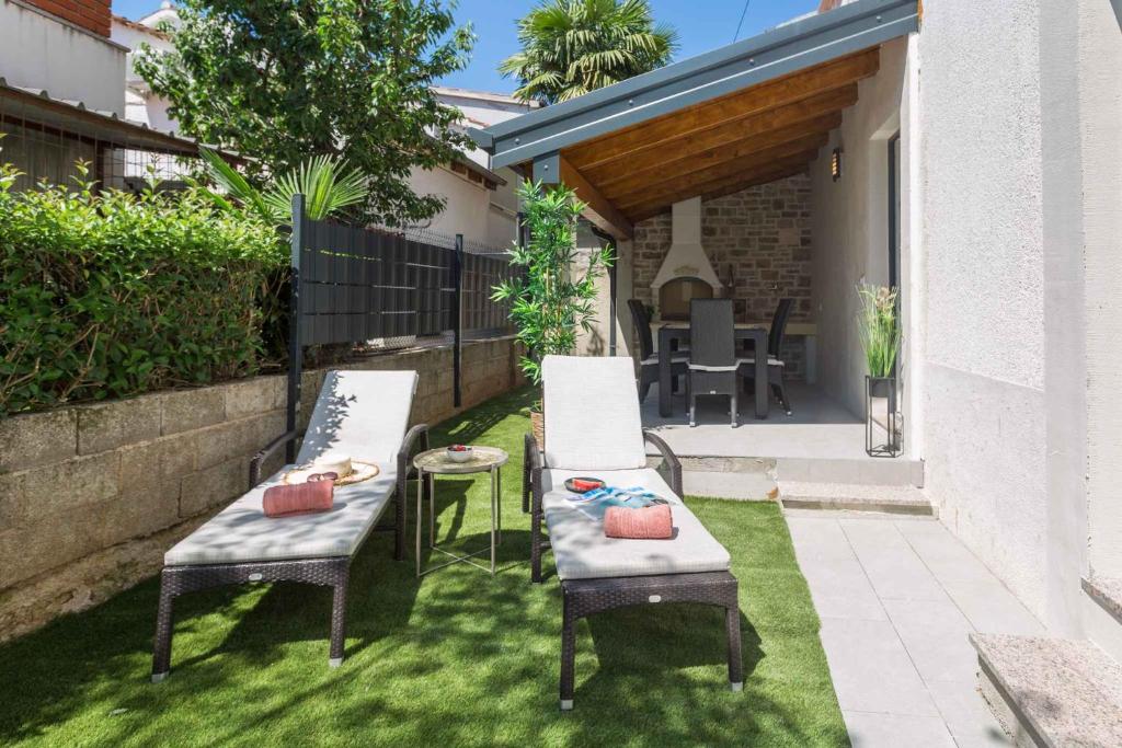 een achtertuin met 2 stoelen, een tafel en een patio bij Apartments in Porec - Istrien 43009 in Poreč