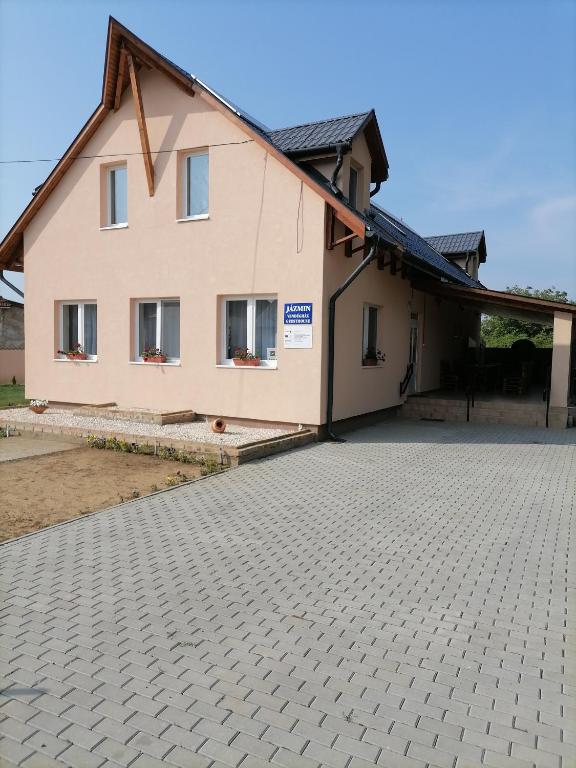 a house with a brick driveway in front of it at Jázmin Vendégház 