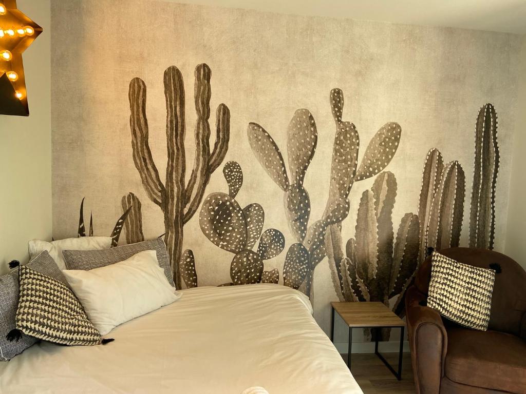 een slaapkamer met een bed met een cactus muurschildering aan de muur bij Le Nid Bourguignon in Chalon-sur-Saône