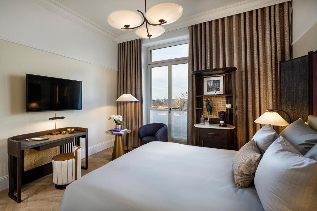 a hotel room with a bed and a desk and a window at Small Luxury Hotel Ambassador Zurich in Zürich