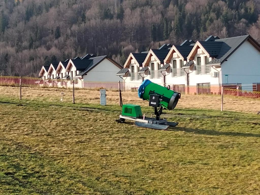 una máquina verde en un campo frente a las casas en Nad Lipami, en Szczyrk