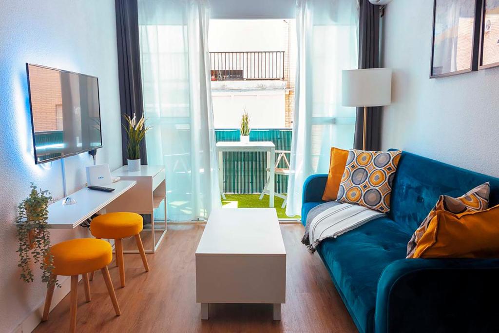 a living room with a blue couch and a desk at Triana Apartment in Seville