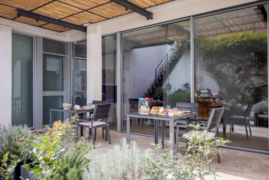 patio ze stołami, krzesłami i oknami w obiekcie Bed & Breakfast Il Carignano w Cagliari