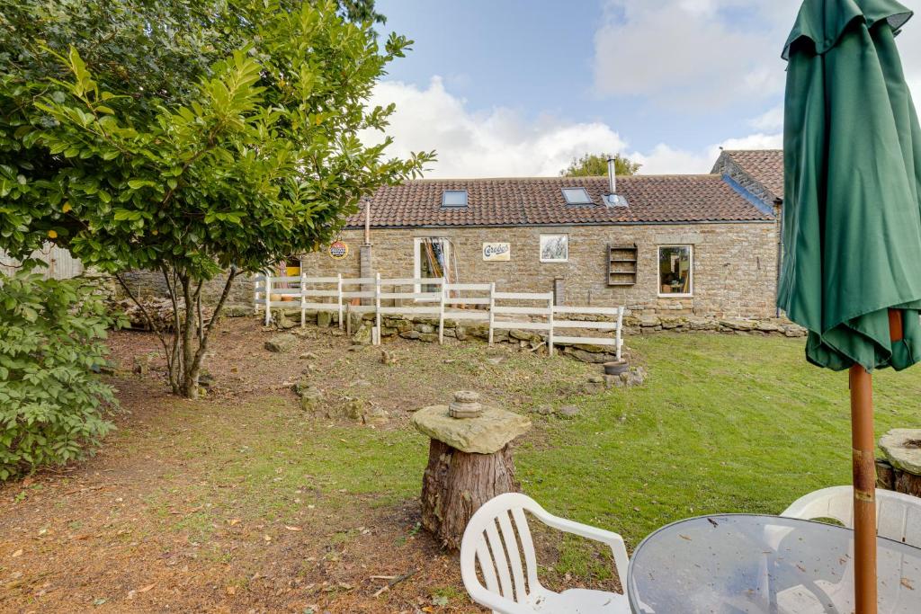 een paraplu en een tafel en stoelen voor een huis bij Family Country Cottage with a private Valley View in Scarborough