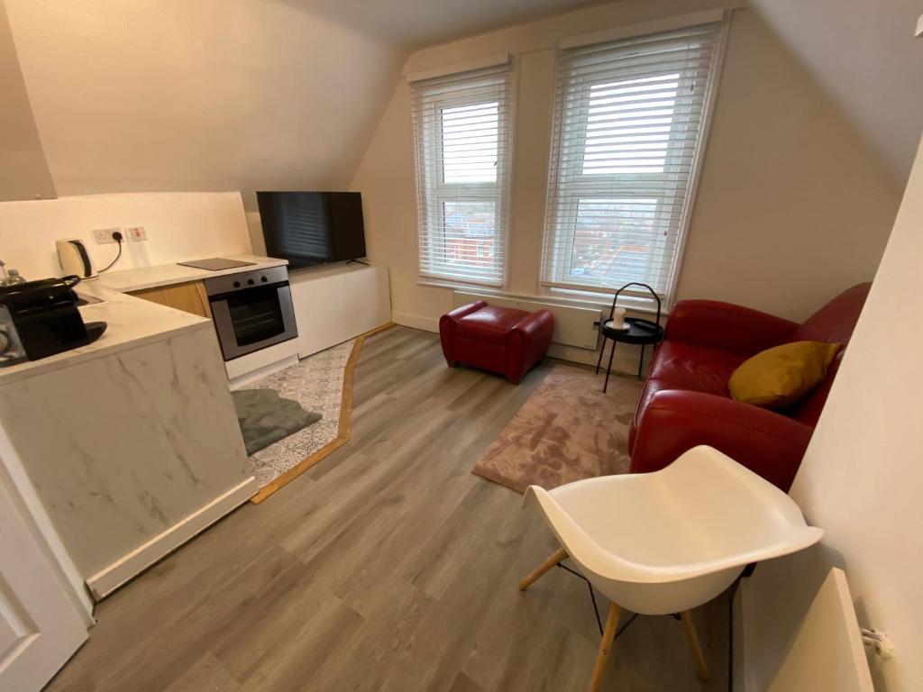 een woonkamer met een rode bank en een keuken bij Cosy flat in London in Londen