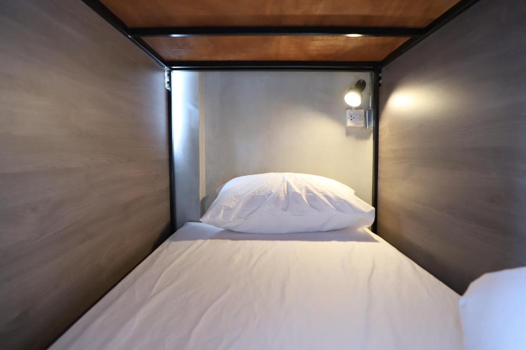a bed with a white pillow in a small room at The Cube Hostel Khaosan in Bangkok