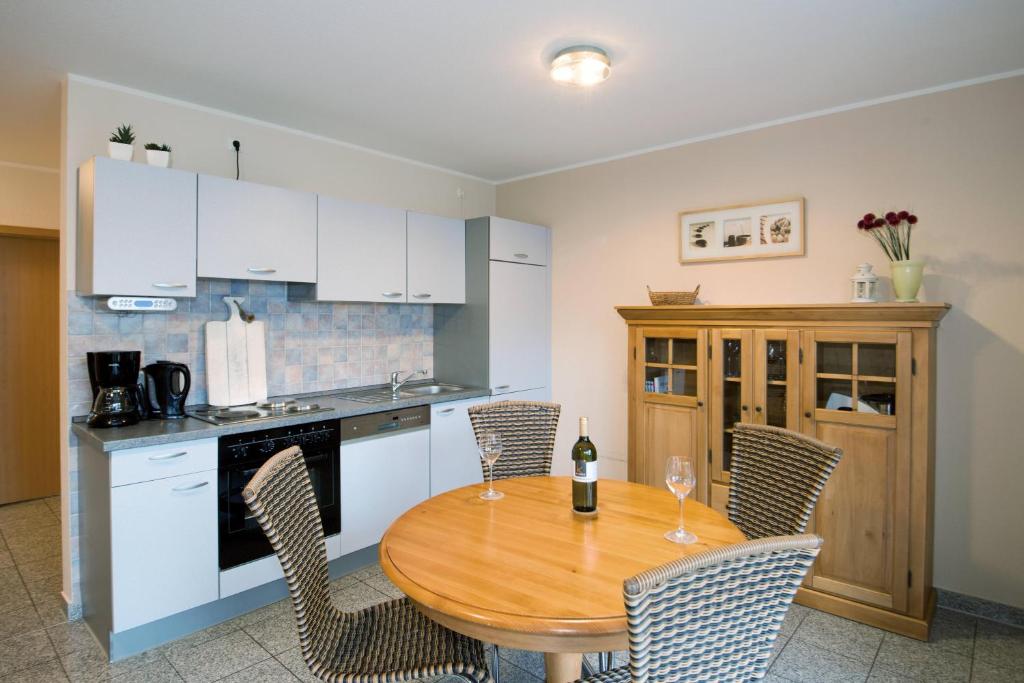 a kitchen with a wooden table and chairs and a kitchen with white cabinets at Ferienwohnung Jacobs EG in Norddeich