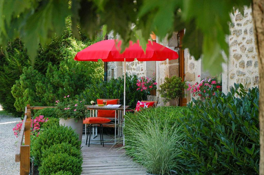 a table with a red umbrella in a garden at Au Grand Fête, B&B à la campagne in Le Fête