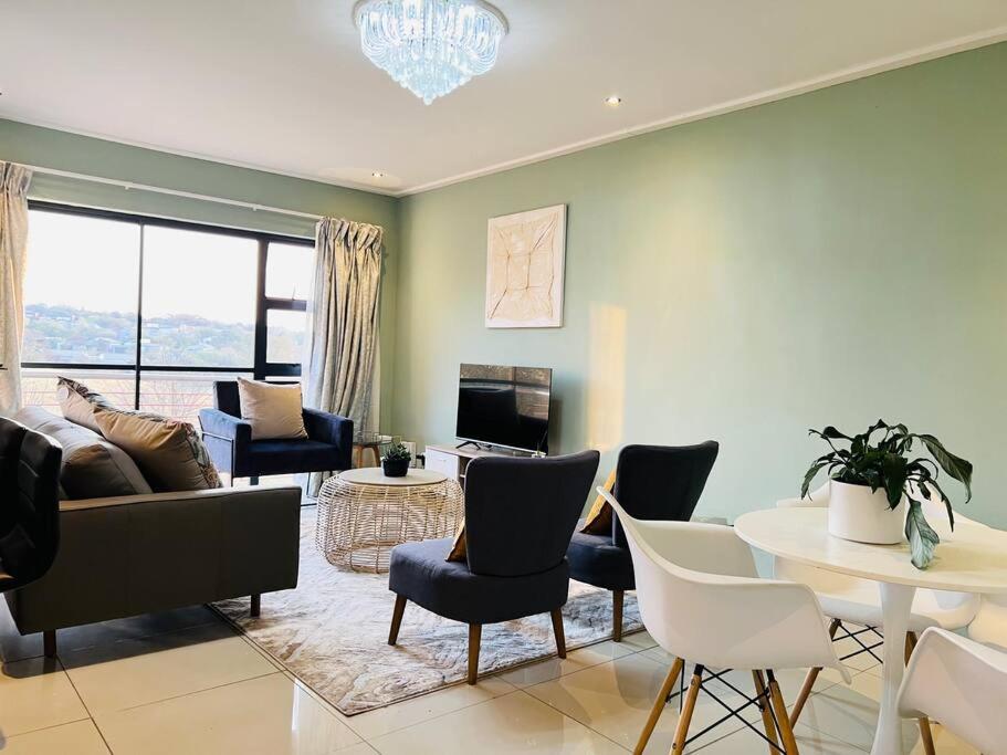 a living room with a couch and chairs and a table at Cozy Self Catering Apartment with Golf Course Views, Jackal Creek Golf Estate in Roodepoort