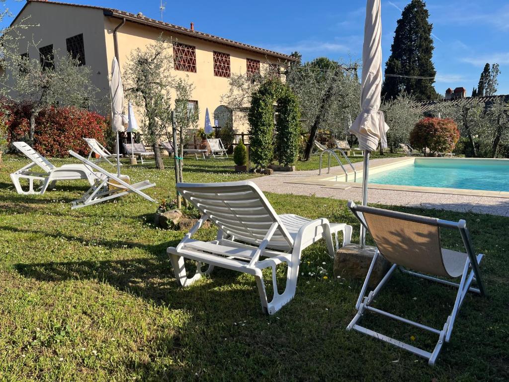 a group of chairs sitting in the grass next to a pool at Agriturismo IL VIAIO in Fiesole