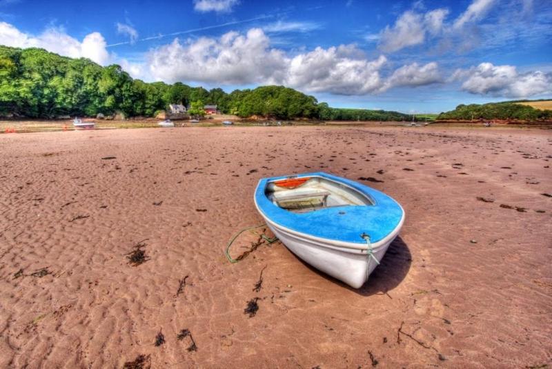 Middle Cottage Sandy Haven Beach في ميلفورد هافن: قارب أبيض وأزرق على شاطئ