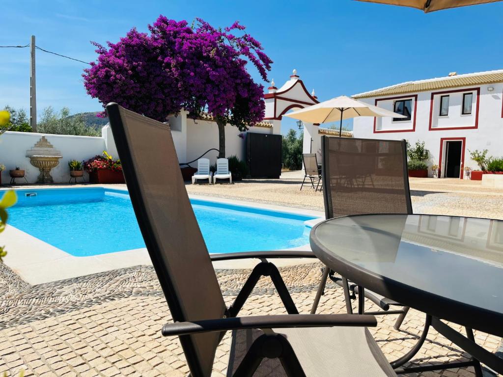 una mesa y sillas junto a una piscina en Cortijo Domínguez - Rural Experience, en Lucena