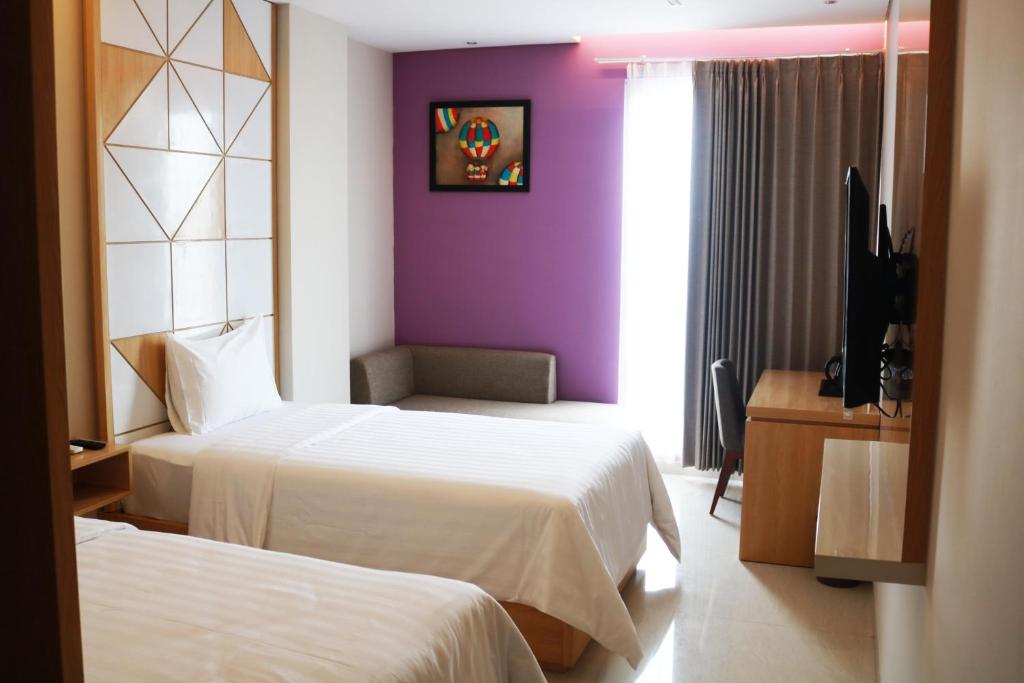泗水的住宿－Surabaya River View Hotel，酒店客房设有两张床和紫色墙壁。