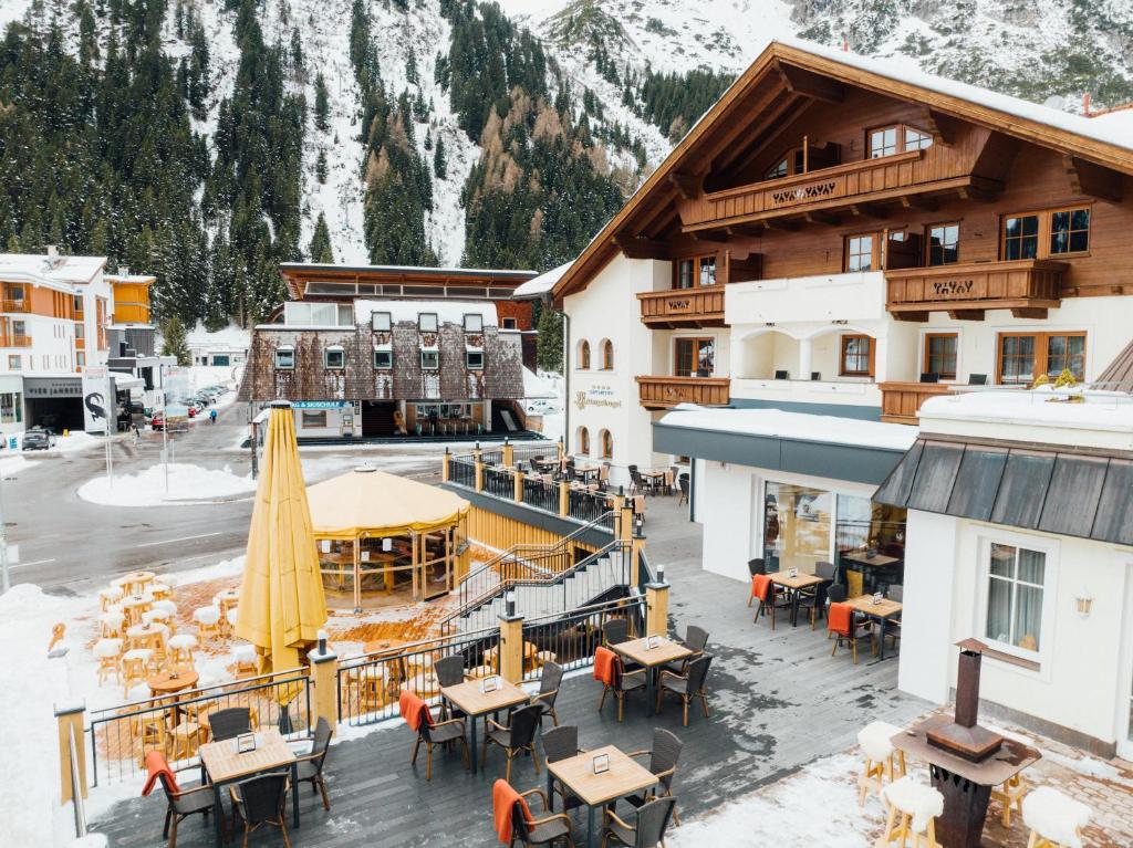an outdoor restaurant with tables and chairs in the snow at Hotel Mittagskogel Pitztal in Sankt Leonhard im Pitztal