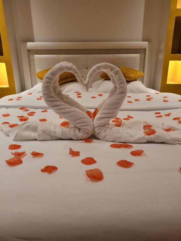 Dos cisnes de toalla haciendo un corazón en una cama en SPA Celyna appartement avec jacuzzi privatif en Lyon