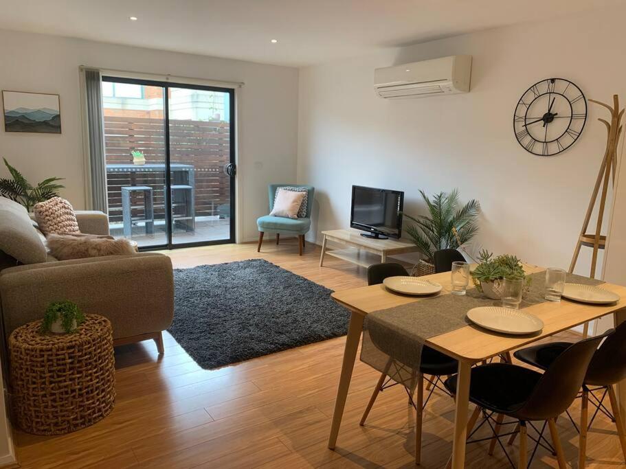 een woonkamer met een bank en een tafel met stoelen bij Affordable 2BR Apartment near Melbourne CBD in Maribyrnong