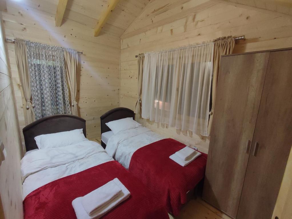 a bedroom with two beds with red and white sheets at Vila Helena in Kolašin