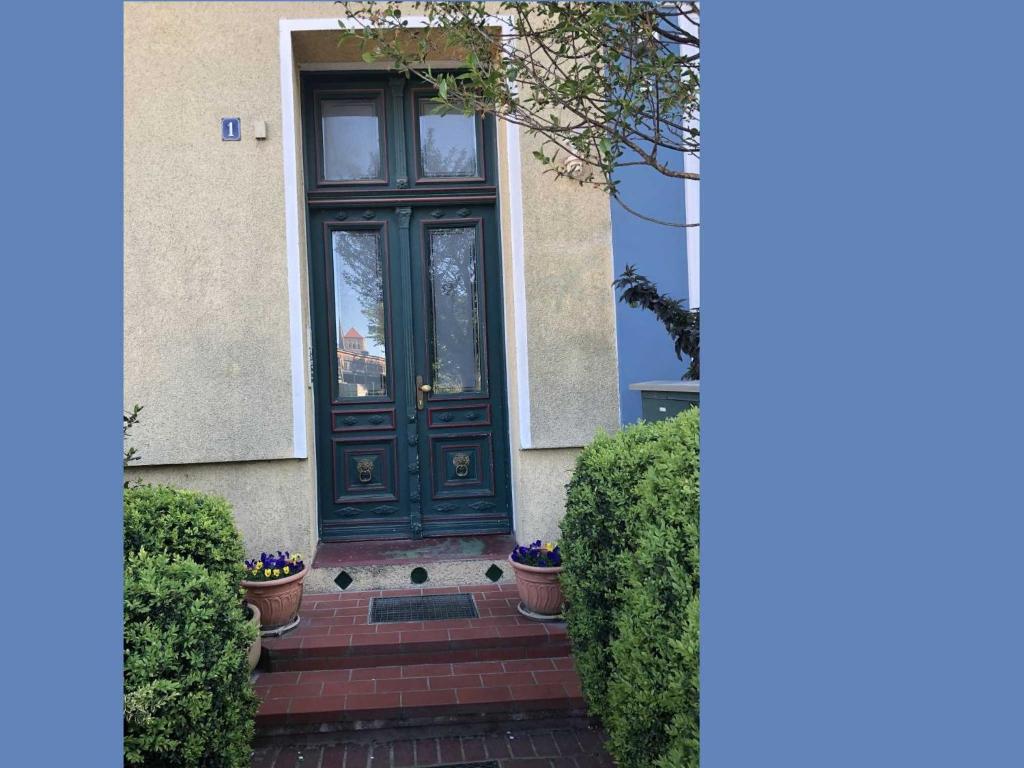 eine grüne Tür auf einem Haus mit Büschen in der Unterkunft Gästezimmer Sprenger - Objekt 25985 in Rostock