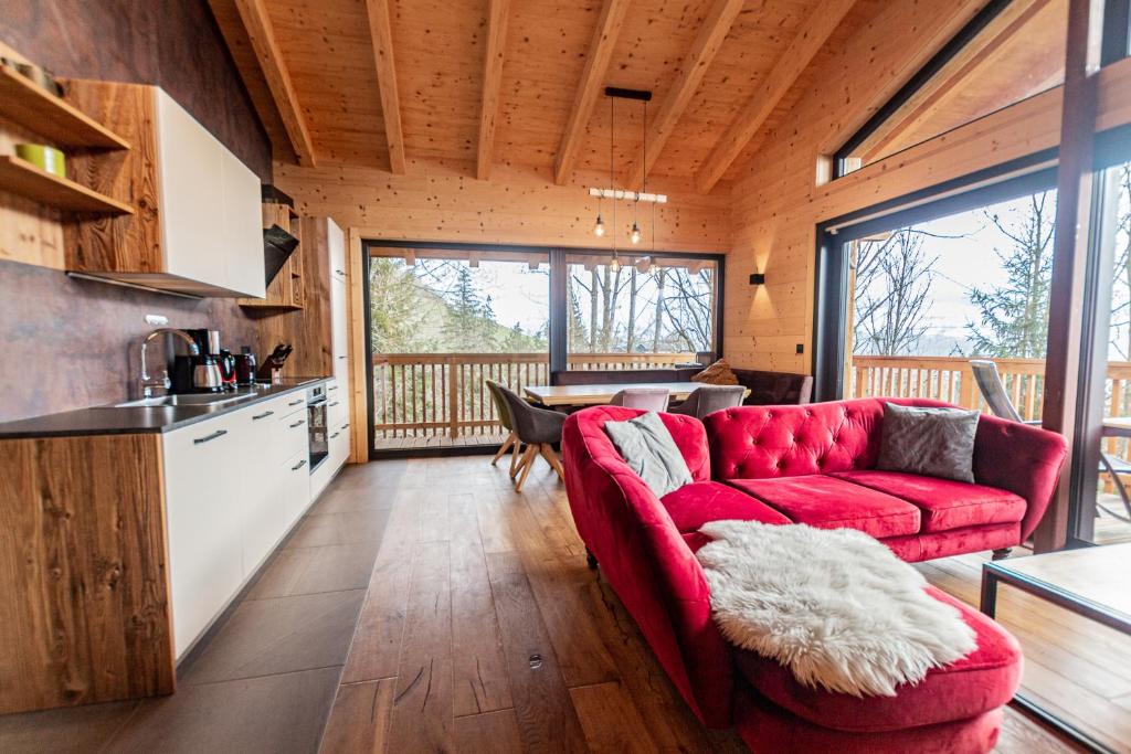 a living room with a red couch and a kitchen at Chalet Dinkel in Niedernsill in Niedernsill