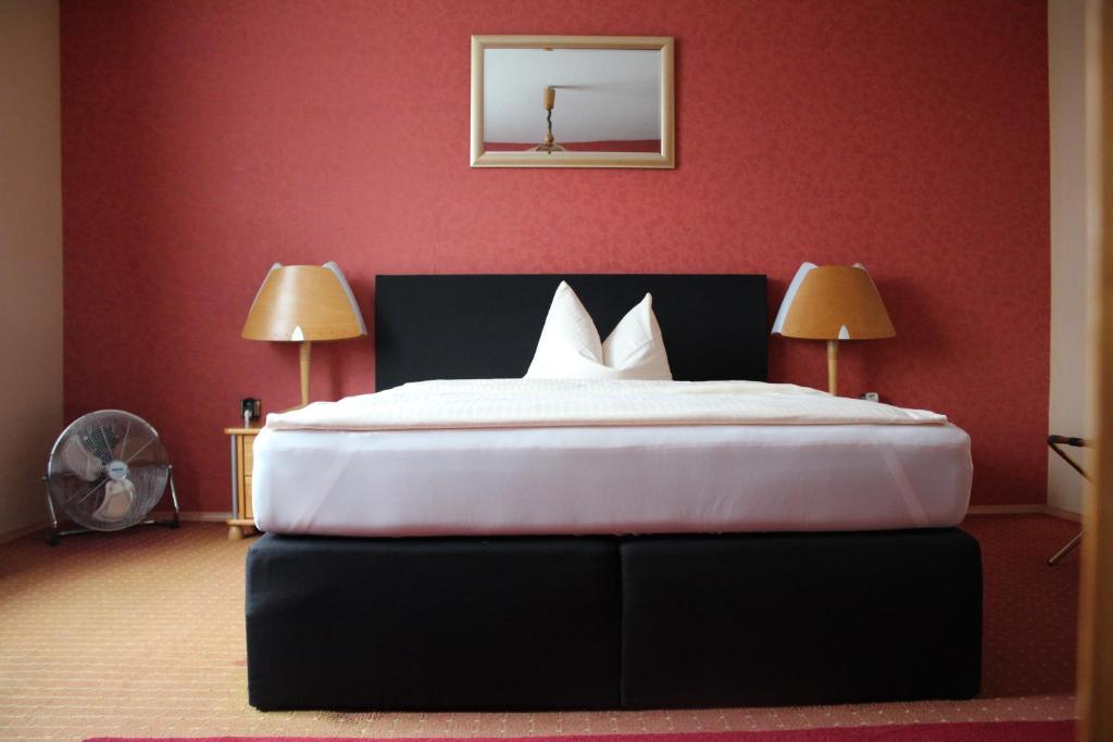 a bedroom with a large bed with red walls at Occhipinti Passione - Restaurant & Hotel - Weyhausen in Weyhausen