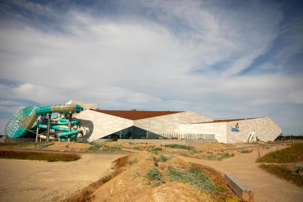 a building with a slide in front of a playground at Lalandia Søndervig in Søndervig