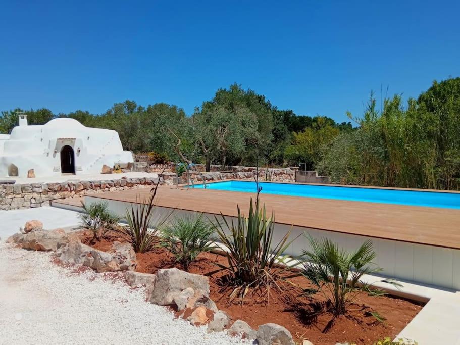 - une piscine dans un jardin paysager avec une maison dans l'établissement Beautiful Trulli in the heart of the Valle d Itria, à Ostuni